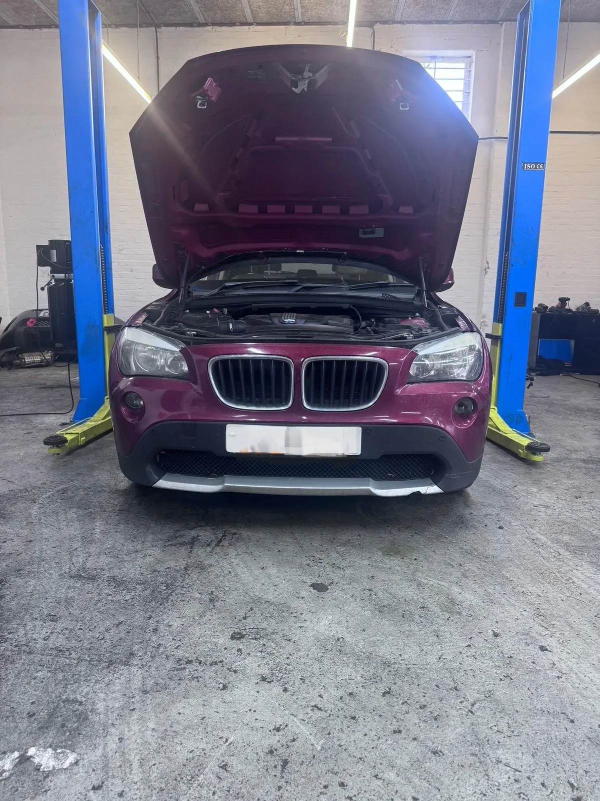 Maroon BMW X1 with hood open for engine service at JLR Engine Specialists – IMI-certified technicians servicing BMW, Jaguar & Land Rover vehicles in UK workshop
