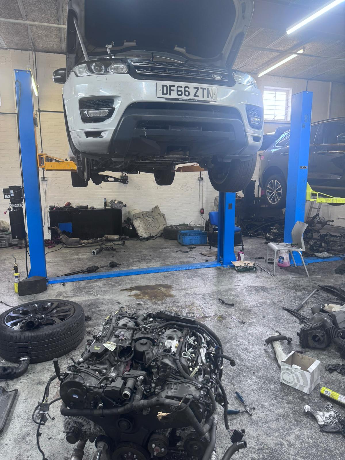 White Land Rover Discovery 4 on lift with engine removed for full rebuild at JLR Engine Specialists – IMI-certified technicians using OEM-spec parts for diesel and petrol engines