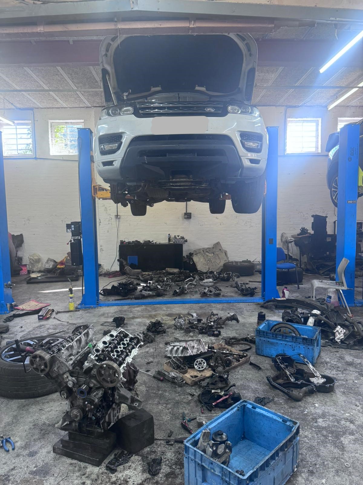White Land Rover Discovery 4 on lift with engine stripped for full rebuild at JLR Engine Specialists – IMI-certified technicians working on diesel engines with OEM-spec parts