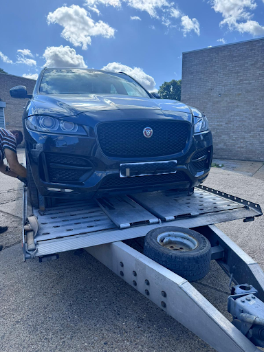 Blue Jaguar F-Pace on flatbed transporter being collected for engine repair – JLR Engine Specialists offers nationwide fitting with 12-month unlimited mileage warranty